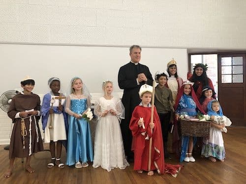 Children dressed as their patron saints with the priest