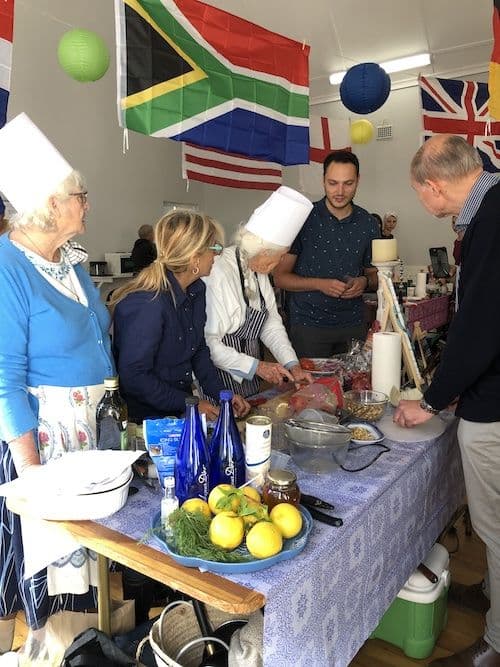 Parishioners cooking together in the hall under flags of many nations